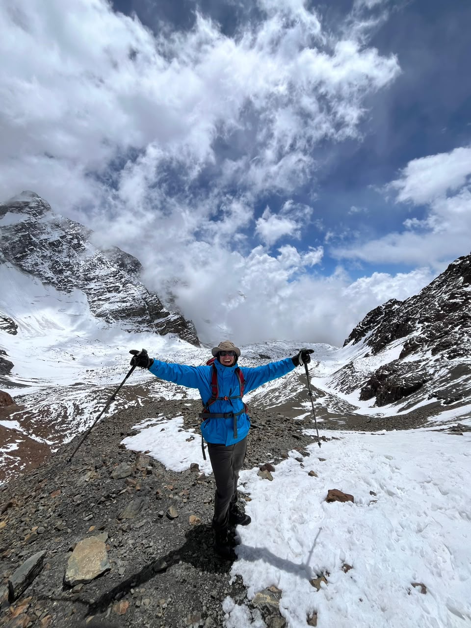 Francisco con bastones y los brazos en alto en la nieve, frente a una montaña nevada