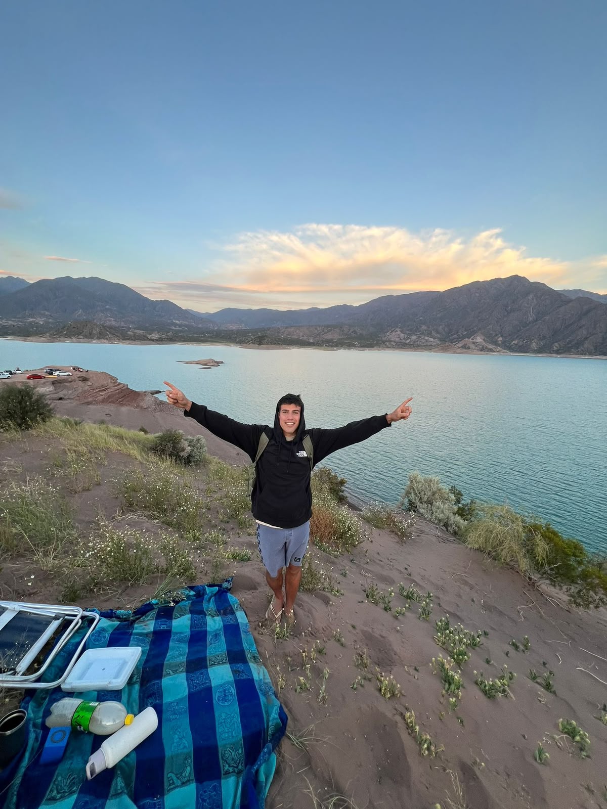 Francisco con los brazos en alto frente a un dique al atardecer